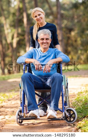loving wife taking her disabled husband for a walk at the park