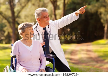 friendly middle aged medical doctor and senior patient outdoors for a walk