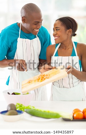 cute african couple preparing a salad in the kitchen
