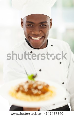 close up portrait of african chef in hotel kitchen presenting pasta