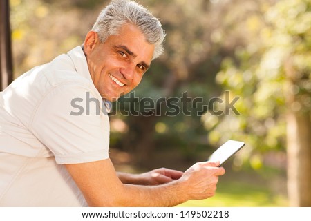 handsome middle aged man holding tablet computer outdoors