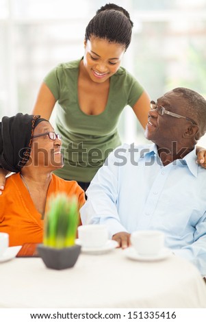 beautiful african girl talking to senior parents at home