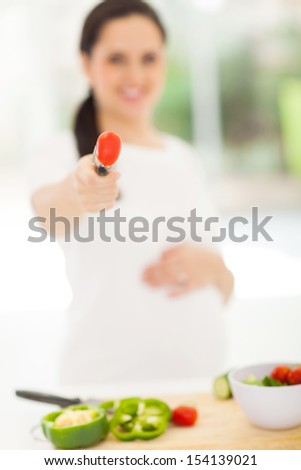 close up of pregnant woman giving fresh tomato
