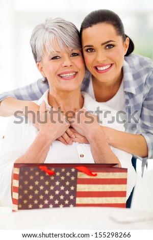 happy mature woman receiving gift from daughter on mother\'s day