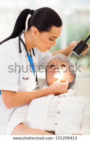 beautiful dermatologist inspecting middle aged patient\'s skin in office