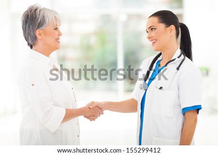 attractive medical doctor handshaking with middle aged patient