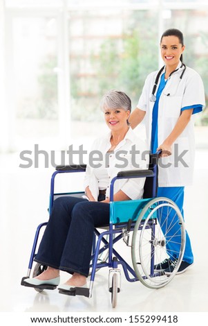 pretty young nurse pushing middle aged patient on wheelchair
