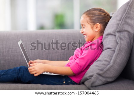 pretty little girl using laptop on sofa at home