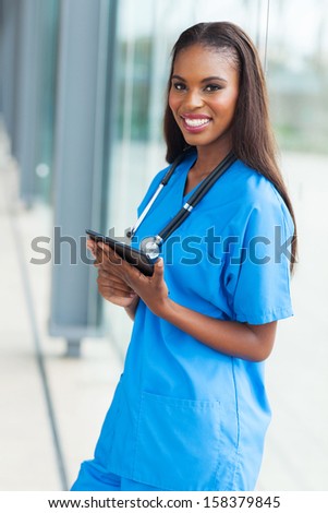 beautiful young african nurse holding tablet computer in office