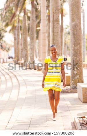 attractive african woman walking down the urban street