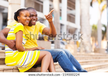 happy african american couple sitting outdoors in the city