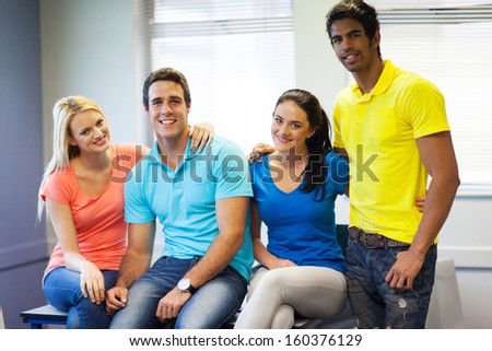 four college friends in classroom looking at the camera