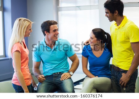 group of happy university friends talking during break in lecture hall