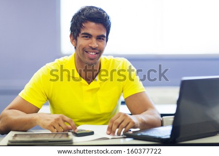 cheerful male indian college student in lecture room