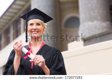 beautiful senior graduate holding certificate in front of university building