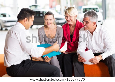 indian car dealer explaining sales contract to the family buying a car