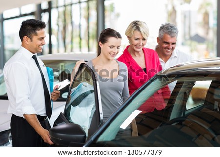 handsome car salesman showing a new car to a family