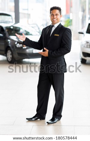 cheerful indian car salesman doing welcoming gesture