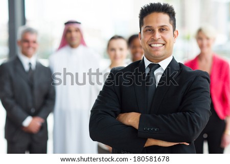 cheerful young indian businessman with team on background