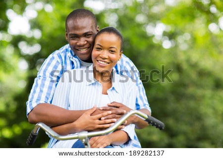 happy african couple on one bike relaxing in forest