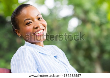 carefree young black woman sitting at the park