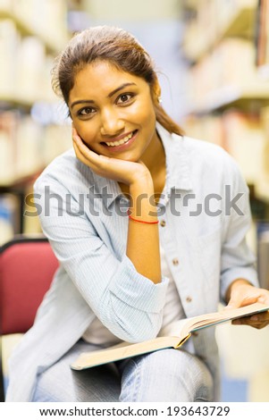 beautiful indian university student reading a book in library