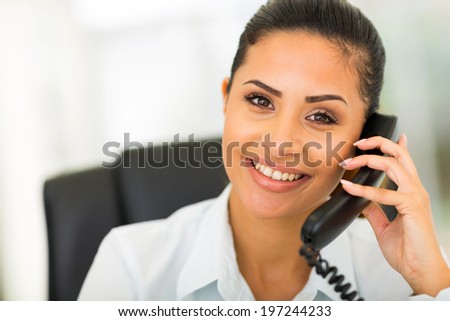 beautiful young businesswoman using landline phone