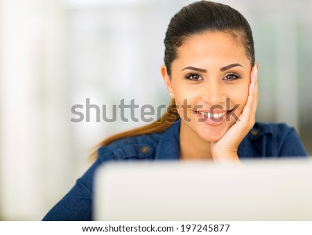 attractive young woman in front of laptop and looking at the camera