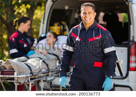 handsome paramedic with colleague and patient on background
