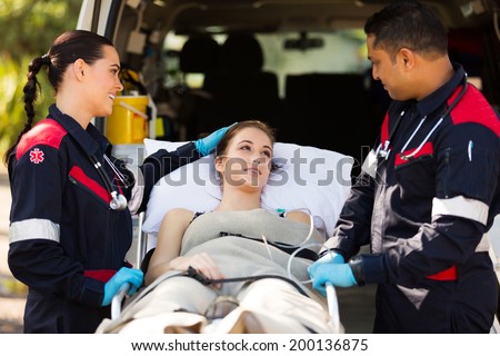 friendly paramedic comforting young patient before transporting her to hospital