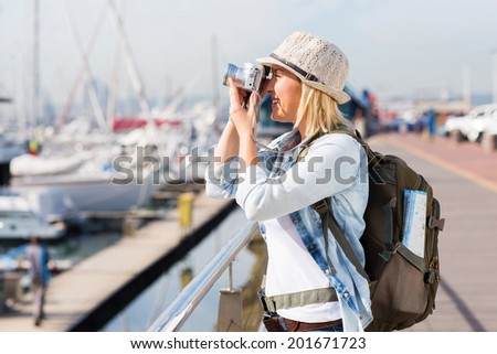 happy tourist taking pictures at the harbor with a digital camera