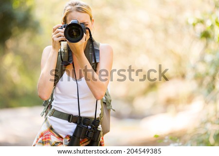 young hiker taking photos in mountain valley