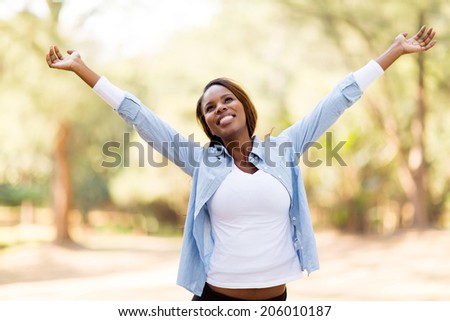 happy african woman with arms outstretched outdoors
