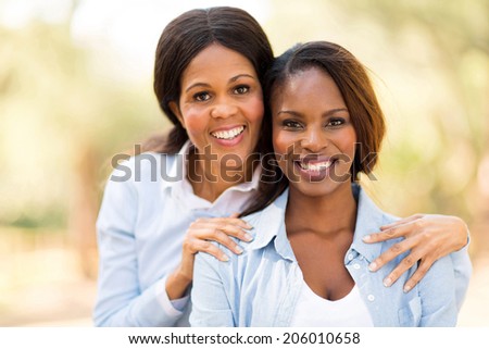portrait of happy middle aged african mother and adult daughter outdoors