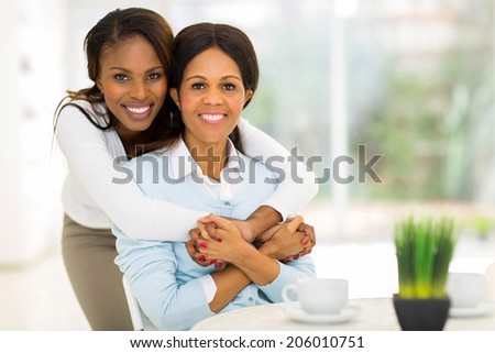 loving african daughter hugging middle aged mother at home