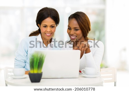 happy mid age african mother and daughter using laptop computer at home