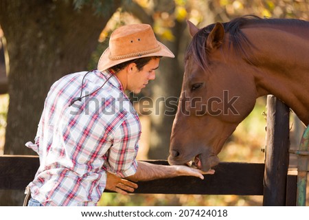 cowboy feeding a horse out of hand