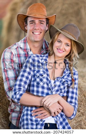 young farming couple hugging inside barn