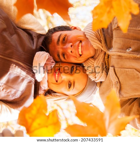 underneath view of young couple holding autumn leaves in forest