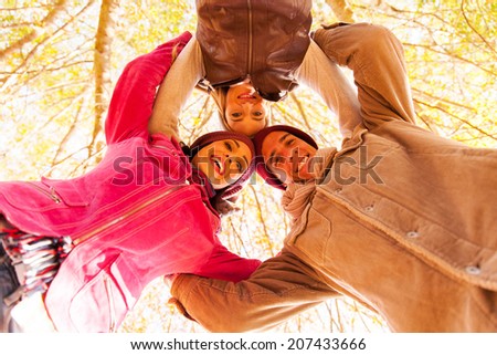 underneath view of group of friends in a circle looking down in autumn forest