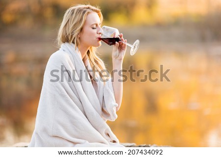 beautiful blond woman drinking red wine at sunset