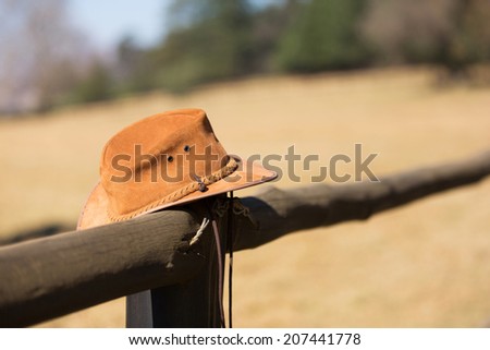 cowboy hat hanging on farm fence