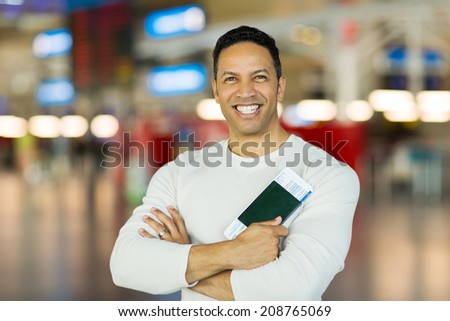 mid age man holding passport and boarding pass at airport
