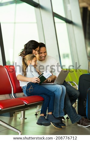 cute family using laptop at airport while waiting for their flight