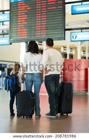 rear view of family checking flight information at airport
