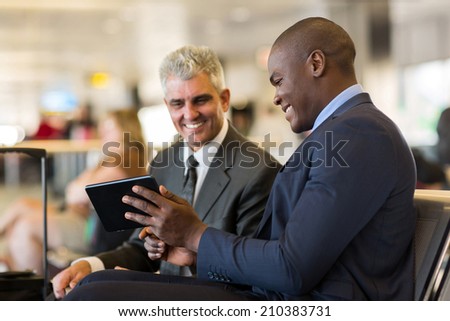 cheerful business travelers using tablet computer at airport