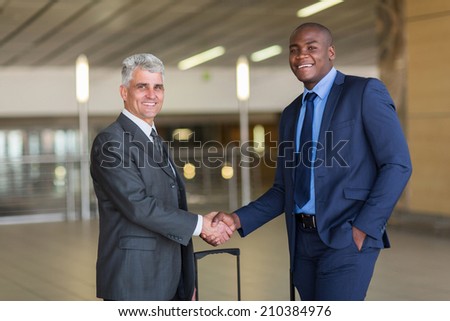 portrait of business travellers greeting at airport