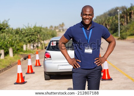 happy african driving instructor standing in testing ground