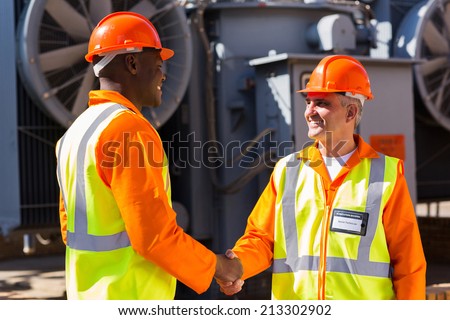 friendly power company co-workers hand shaking in electrical substation