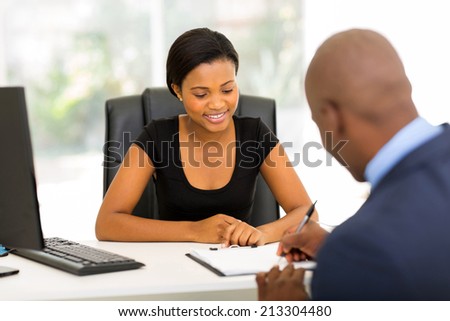 rear view of african businessman signing contract in office